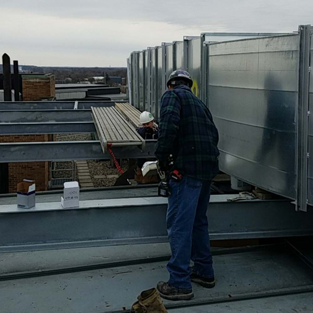 Workers inspecting an HVAC system on a rooftop