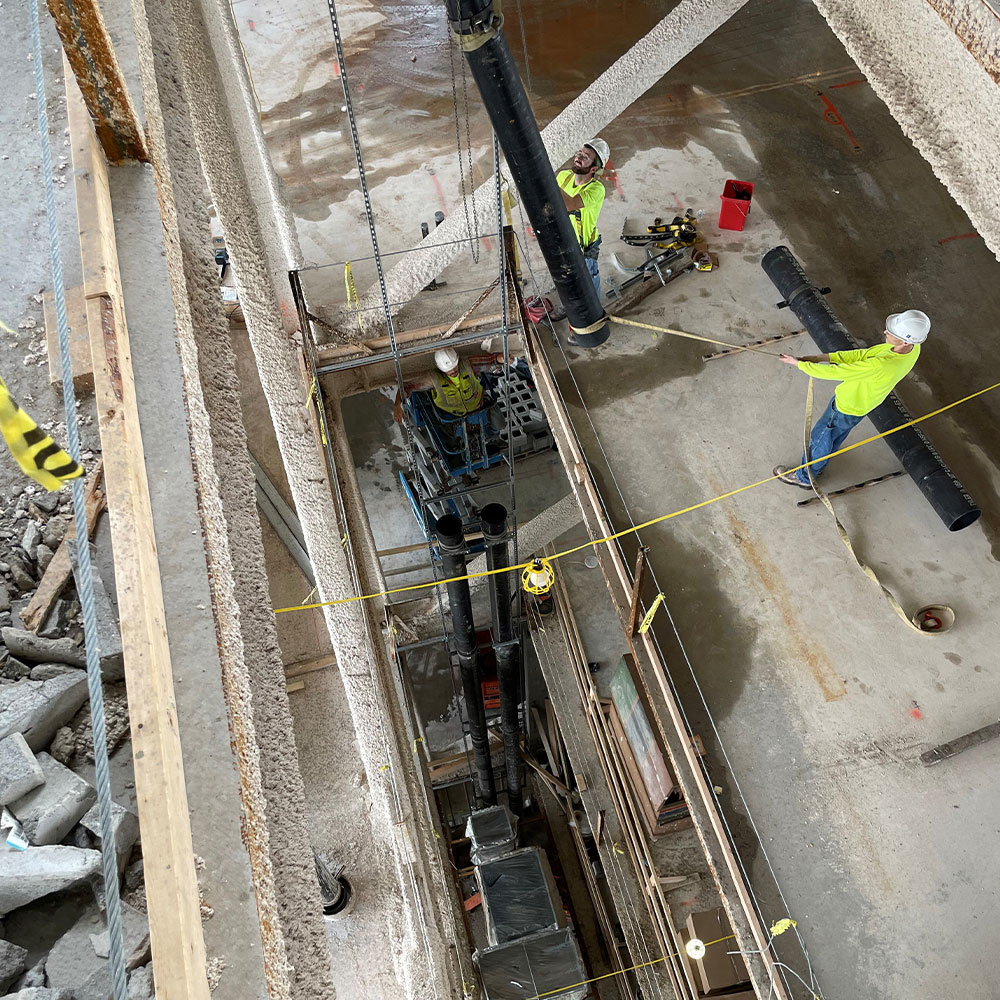 three MCM workers working across multiple floors installing vertical plumbing pipes